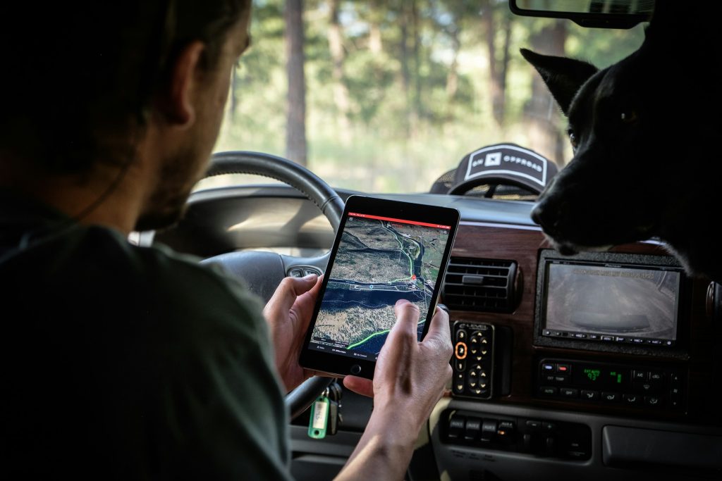 Un homme et un chien dans une voiture regardant une carte sur une tablette